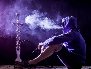 bir adam siyah bir arka plan, aydınlatma güzel bir nargile sigara içiyor.