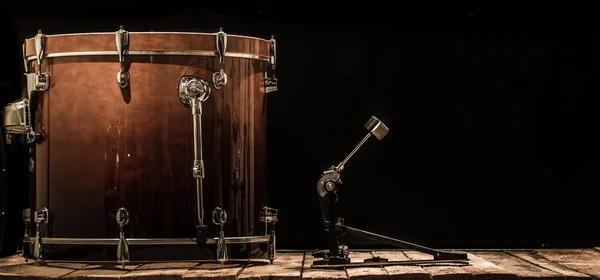 percussion instrument, bass drum with pedal on wooden boards with a black background