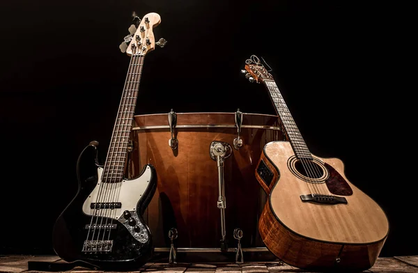 musical instruments, bass drum barrel acoustic guitar and bass guitar on a black background