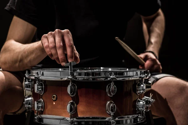 Homem ajusta um instrumento de percussão, conceito musical com o tambor de trabalho — Fotografia de Stock