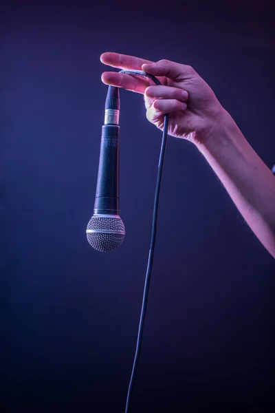 Hand with microphone on a black background, the music concept, beautiful lighting on the stage — Stock Photo, Image