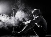 ein Mann raucht eine Wasserpfeife auf schwarzem Hintergrund, schöne Beleuchtung