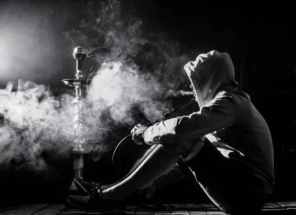 En man röker vattenpipa på svart bakgrund, vacker belysning — Stockfoto