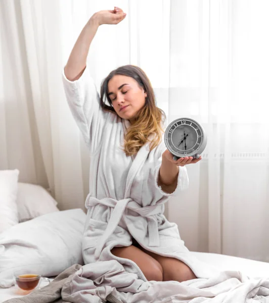 Fille le matin au lit avec horloge — Photo