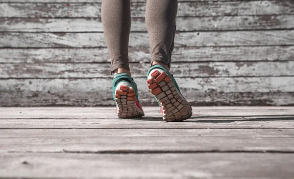Женские ноги в кроссовках на деревянном фоне — стоковое фото