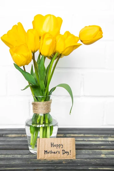 Cartolina Festa della mamma e tulipani gialli su sfondo di legno — Foto Stock