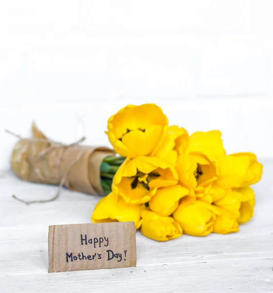 Pohlednice den matek a žluté tulipány na dřevěné pozadí — Stock fotografie