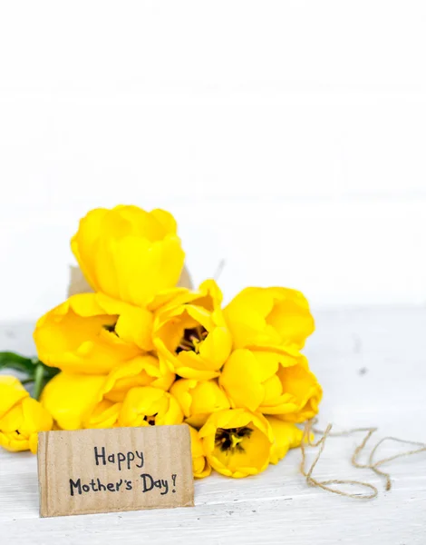 Pohlednice den matek a žluté tulipány na dřevěné pozadí — Stock fotografie