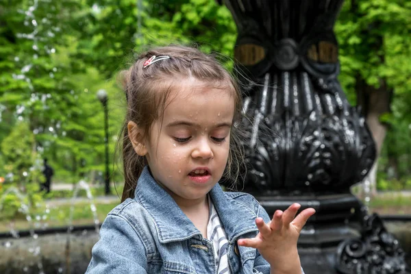 Маленькая милая девочка мочит руки в фонтане — стоковое фото