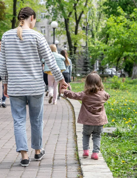 Маленькая девочка идет рука об руку с мамой — стоковое фото