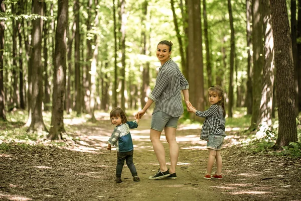 Madre con hijas jóvenes caminan en el bosque — Foto de Stock