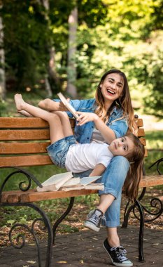 Anne ve kızı bir bankta bir kitap okuma