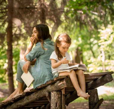 Anne ve kızı parkta bir kitap okumak
