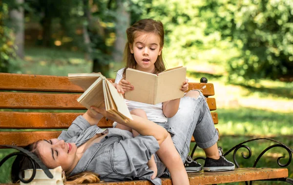 Μαμά και κόρη σε ένα παγκάκι διαβάζοντας ένα βιβλίο — Φωτογραφία Αρχείου