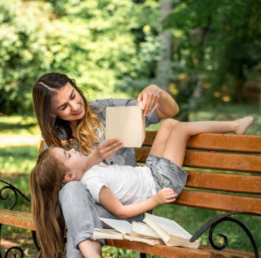 Anne ve kızı bir bankta bir kitap okuma