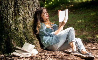 Kız ağaca yakınındaki bir kitap okuma