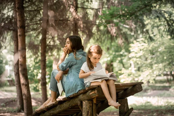 Mutter und Tochter lesen im Park ein Buch — Stockfoto