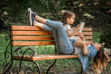 Anne ve kızı bir bankta bir kitap okuma
