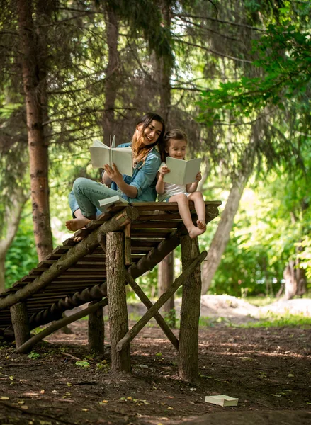 mother and daughter read a book in the park