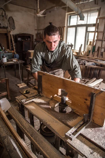 A man works on the machine with the wooden product — Stock Photo, Image