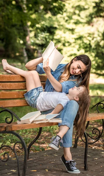 Mamá e hija en un banco leyendo un libro — Foto de Stock