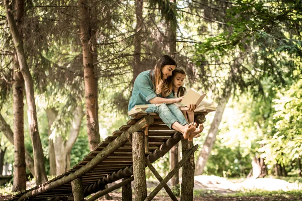 Mutter und Tochter lesen im Park ein Buch — Stockfoto