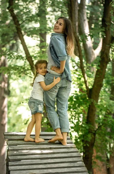Мама и маленькая дочь вручную идут по деревянному мосту — стоковое фото