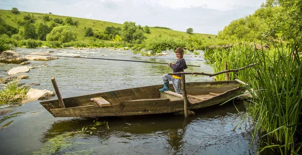 Niño con caña de pescar pesca en un barco de madera — Foto de Stock