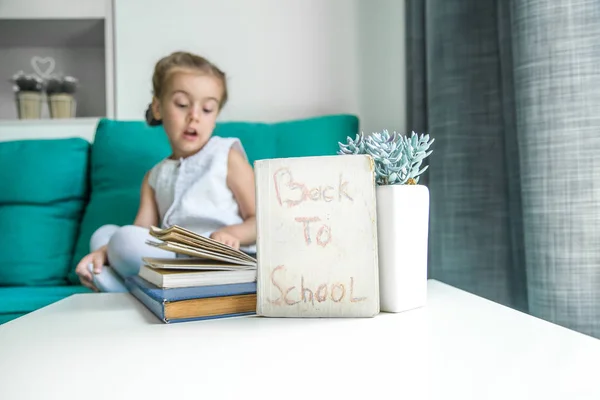 Fille assise avec un livre à la main retour à l'école — Photo