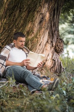Genç adam bir kitap okuma ağaca