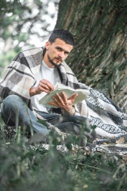 Genç adam bir kitap okuma ağaca