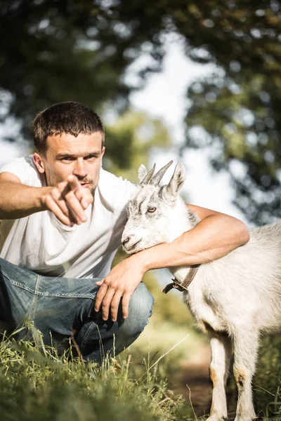 Młody człowiek w przyrodzie z kozą — Zdjęcie stockowe