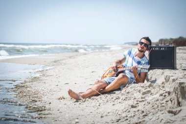 adam müzik aletleri ile sahilde