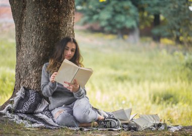 bir ağaç bir kitap okuma yakınındaki bir genç kız