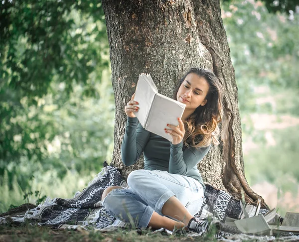 bir ağaç bir kitap okuma yakınındaki bir genç kız