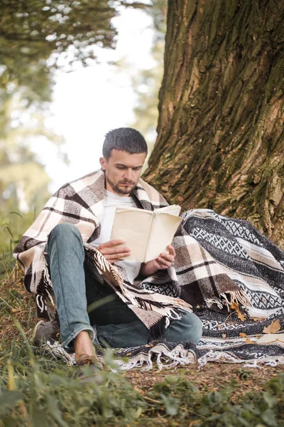 Genç adam bir kitap okuma ağaca — Stok fotoğraf