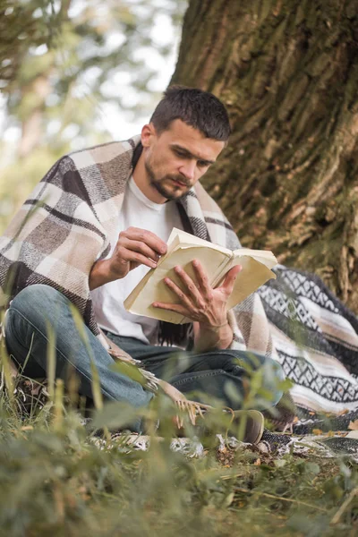 Genç adam bir kitap okuma ağaca — Stok fotoğraf