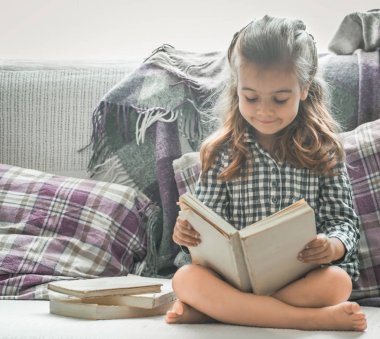 Küçük kız kanepede kitap okuma
