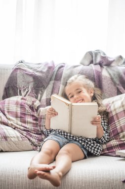 Küçük kız kanepede kitap okuma