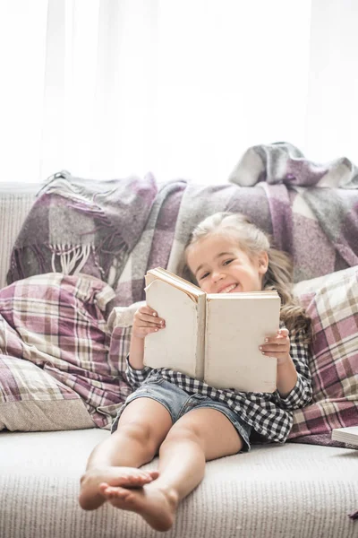Küçük kız kanepede kitap okuma
