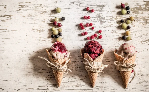 Конус вафельного мороженого с ягодами на деревянном фоне — стоковое фото