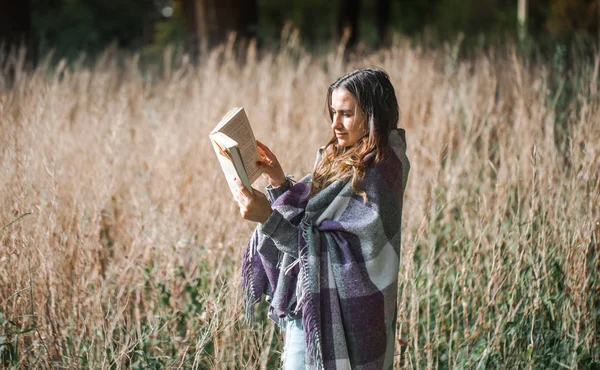 Jovem em um campo lendo um livro — Fotografia de Stock