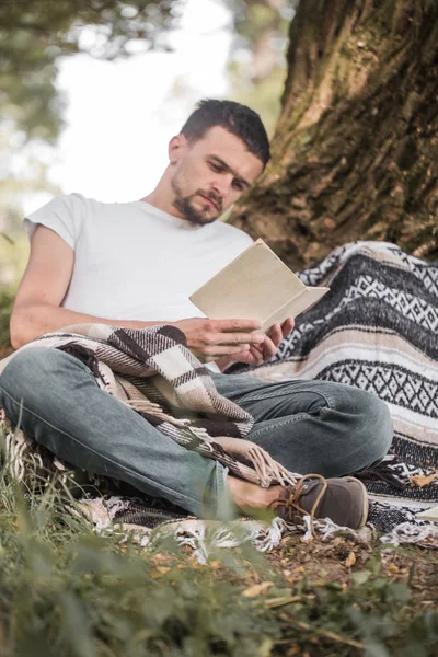 Genç adam bir kitap okuma ağaca — Stok fotoğraf