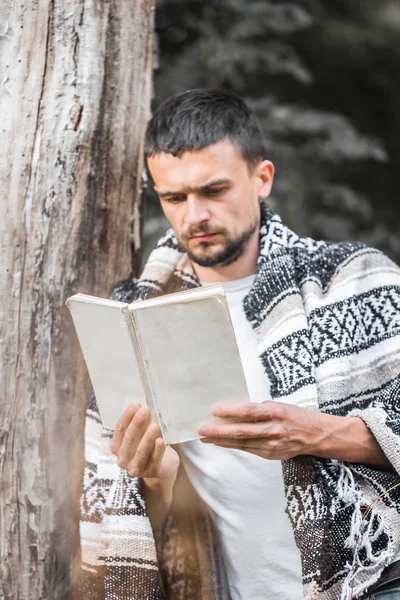 Genç adam bir kitap okuma ağaca — Stok fotoğraf