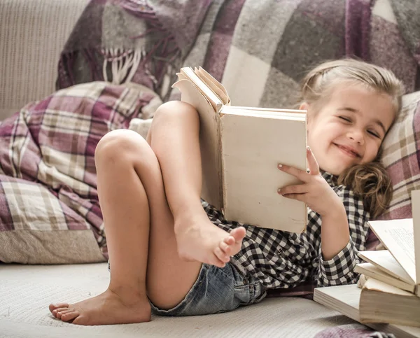 Küçük kız kanepede kitap okuma