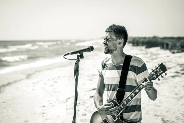 Rock am Strand, der Musiker spielt Gitarre und singt ins Mikrofon, das Konzept der Freizeit und Kreativität — Stockfoto