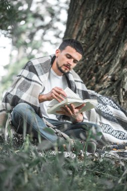 Genç adam bir kitap okuma ağaca