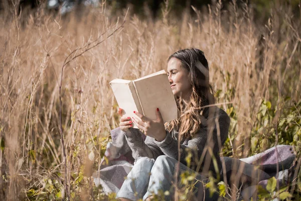 Fiatal lány, egy mezőn egy könyvet olvas — Stock Fotó