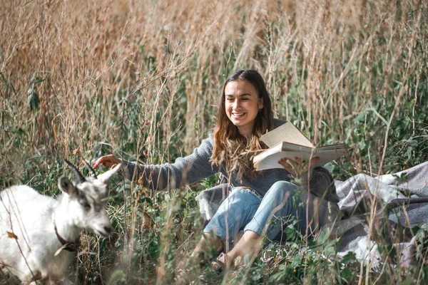Молодая девушка на поле читает книгу — стоковое фото