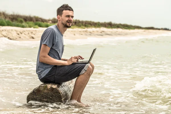 bilgisayar ile plajda çalışan adam